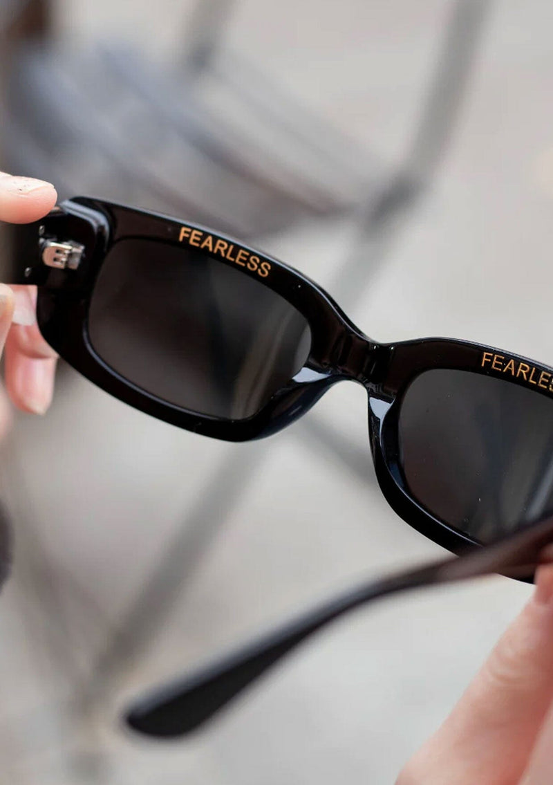[Color: Black] A classic rounded rectangular frame in a black frame, made with biodegradable acetate. With polarized lenses and the word fearless on the inner frame.
