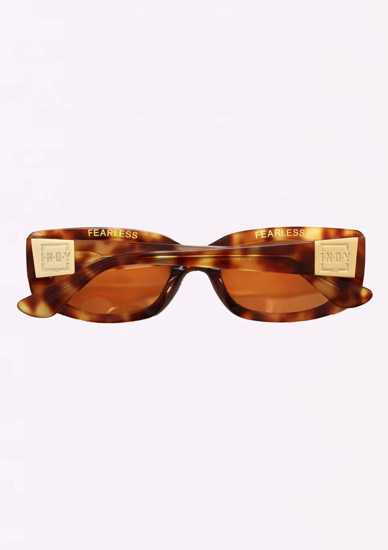 [Color: Tortie] A classic rounded rectangular frame in a brown tortoiseshell frame, made with biodegradable acetate. With polarized lenses and the word fearless on the inner frame.