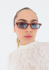 [Color: Blue] A pair of slim, rectangle amber tortoise acetate frames with blue lenses. Made by INDY