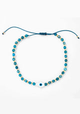 [Title: Apatite]  An adjustable healing bracelet, crafted on a durable nylon cord with a mother of pearl hamsa stone, gold-plated hardware and teal blue natural gemstones. Designed by Kindred Row.