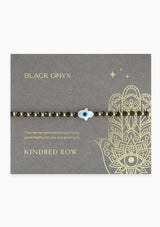 [Title: Black Onyx]  An adjustable healing bracelet, crafted on a durable nylon cord with a mother of pearl hamsa stone, gold-plated hardware and black natural gemstones. Designed by Kindred Row.