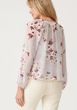 [Color: Dusty Blush/Wine] A back facing image of a blonde model wearing a bohemian resort blouse crafted from textured chiffon and designed in a pink floral print. With a decorative button front, a v neckline, long raglan sleeves, and an elastic waist. 