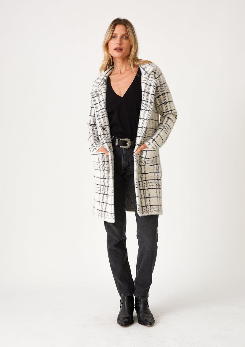 [Color: Cream/Black] A full body front facing image of a blonde model wearing a fuzzy statement sweater coat in a cream and black plaid print. With long sleeves, a notched collar, a snap button front, and side patch pockets. 