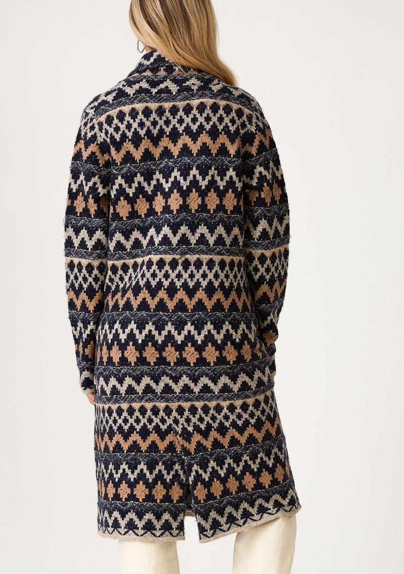 [Color: Navy/Camel] A back facing image of a blonde model wearing a sweater coat in a bohemian blue and brown chevron striped design. With long sleeves, a notched collar, a button front, side patch pockets, and a back vent. 