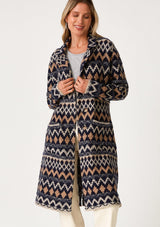 [Color: Navy/Camel] A front facing image of a blonde model wearing a sweater coat in a bohemian blue and brown chevron striped design. With long sleeves, a notched collar, a button front, side patch pockets, and a back vent. 