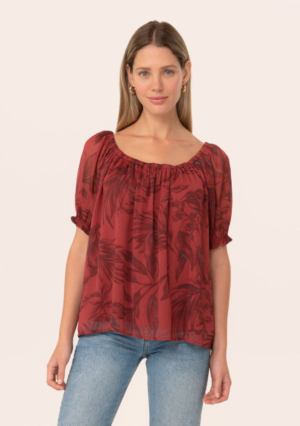 [Color: Wine/Charcoal] A half body front facing image of a blonde model wearing a fall chiffon blouse in a dark red floral and leaf print. With short puff sleeves, an elastic round neckline, and a relaxed, flowy fit.