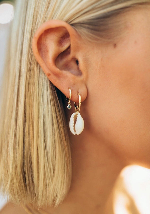 A cool hoop earring with a beachy cowrie shell charm. Crafted from fourteen karat gold on sterling silver, these fun hoop earrings are hypoallergenic and tarnish resistant. 