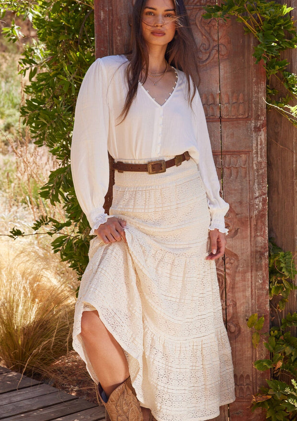 [Color: Natural] A front facing image of a brunette model wearing a bohemian off white lace maxi skirt.