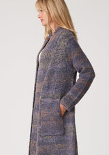 [Color: Denim Multi] A close up side facing image of a blonde model wearing a multi color blue knit long duster cardigan. A bohemian sweater coat with long sleeves, an open front, side pockets, and a rollover collar.