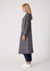 [Color: Denim Multi] A side facing image of a blonde model wearing a multi color blue knit long duster cardigan. A bohemian sweater coat with long sleeves, an open front, side pockets, and a rollover collar.
