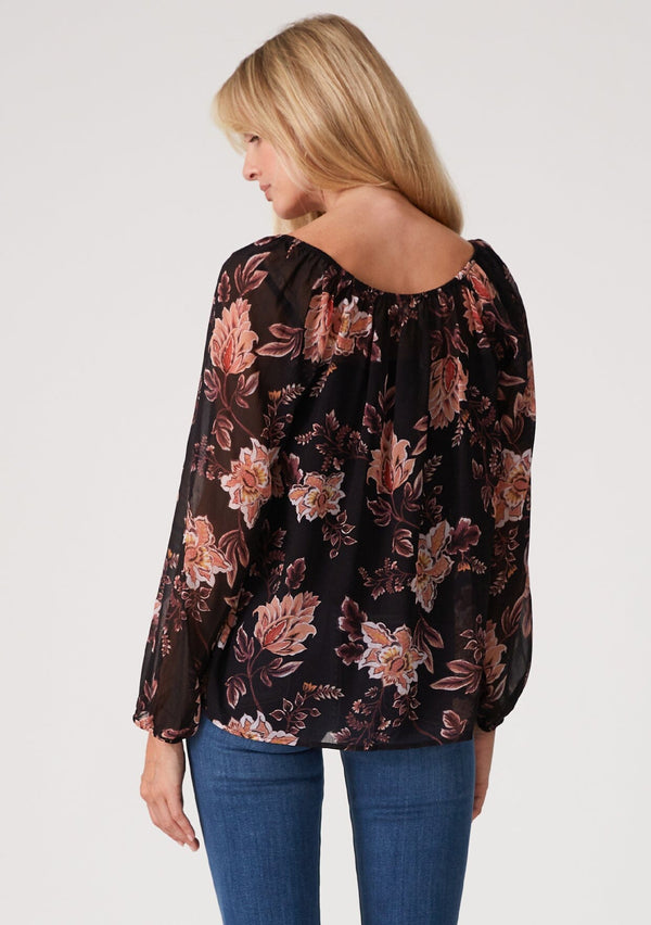 [Color: Black/Dusty Coral] A half body back facing image of a blonde model wearing a flowy bohemian sheer chiffon blouse in a black and coral floral print. With voluminous long sleeves, a split v neckline with ties, and a wide round elastic neckline.