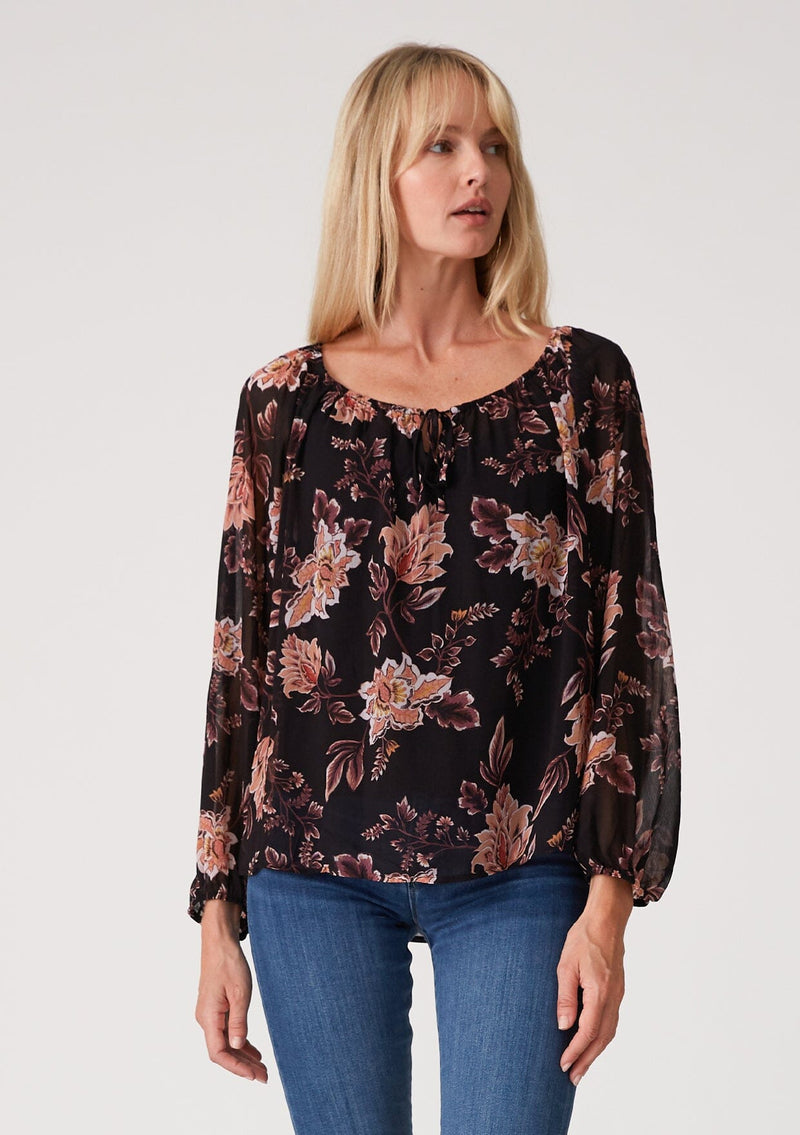 [Color: Black/Dusty Coral] A half body front facing image of a blonde model wearing a flowy bohemian sheer chiffon blouse in a black and coral floral print. With voluminous long sleeves, a split v neckline with ties, and a wide round elastic neckline.