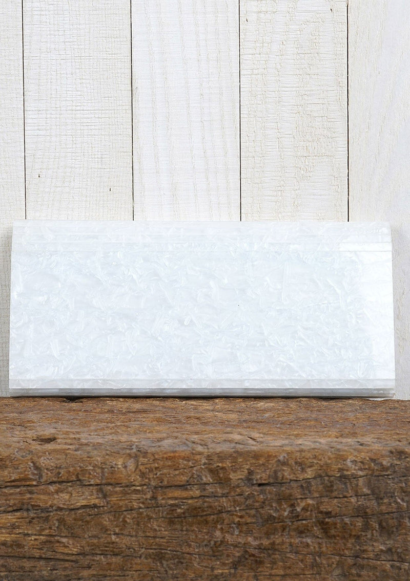 [Color: Pearl] A pearlescent clutch made from molded resin. Features a magnetic closure.