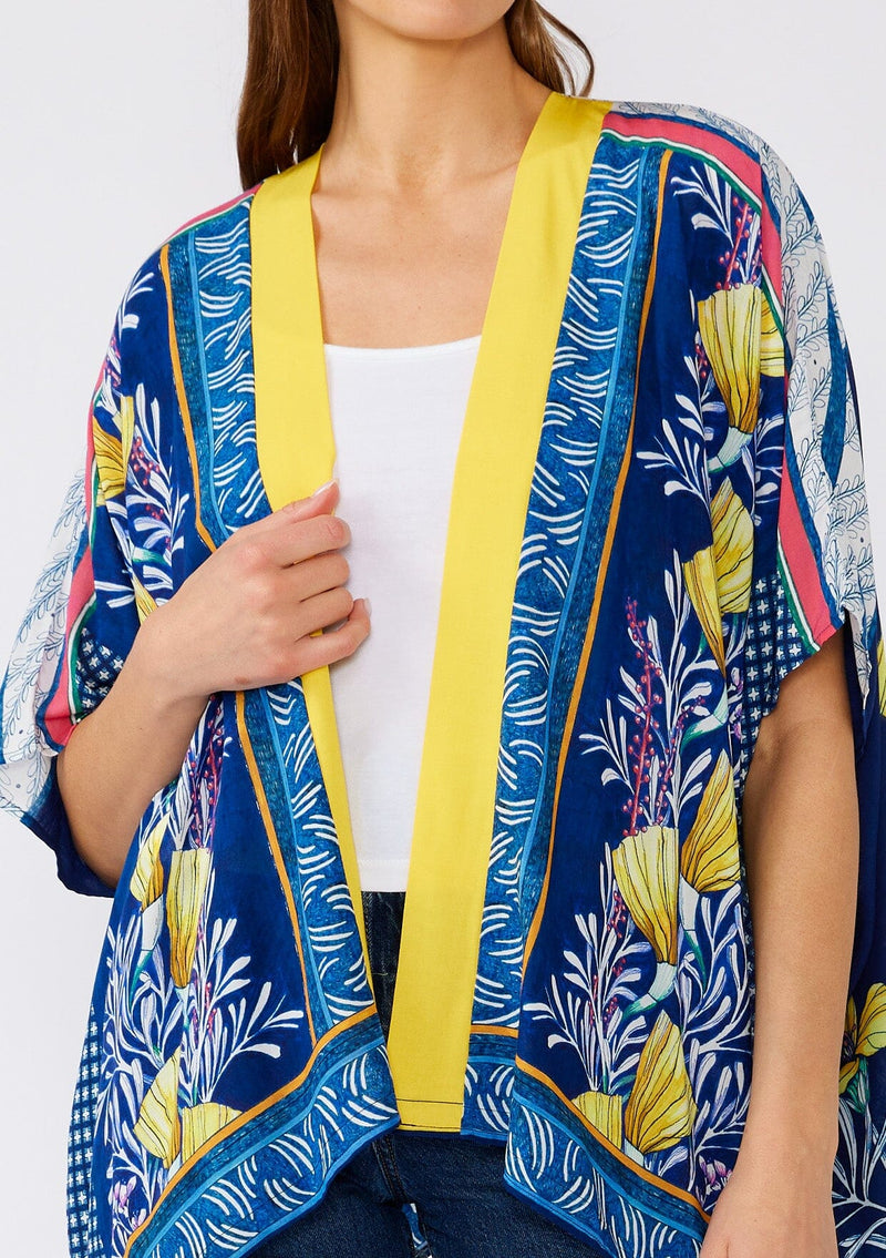 [Color: Navy/Yellow] A close up front facing image of a brunette model wearing a bohemian style kimono top in a navy blue and yellow floral print with a contrast border. A lightweight beach cover up style with half length sleeves, an open front, and a hip length hemline. 