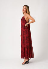 [Color: Wine/Charcoal] A side facing image of a blonde model wearing a dark red chiffon halter maxi dress. With a drawstring halter neckline, a front keyhole, a tiered skirt, and an ultra flowy silhouette.
