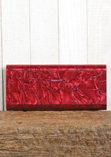 [Color: Lipstick] A pearlescent clutch made from molded resin. Features a magnetic closure.