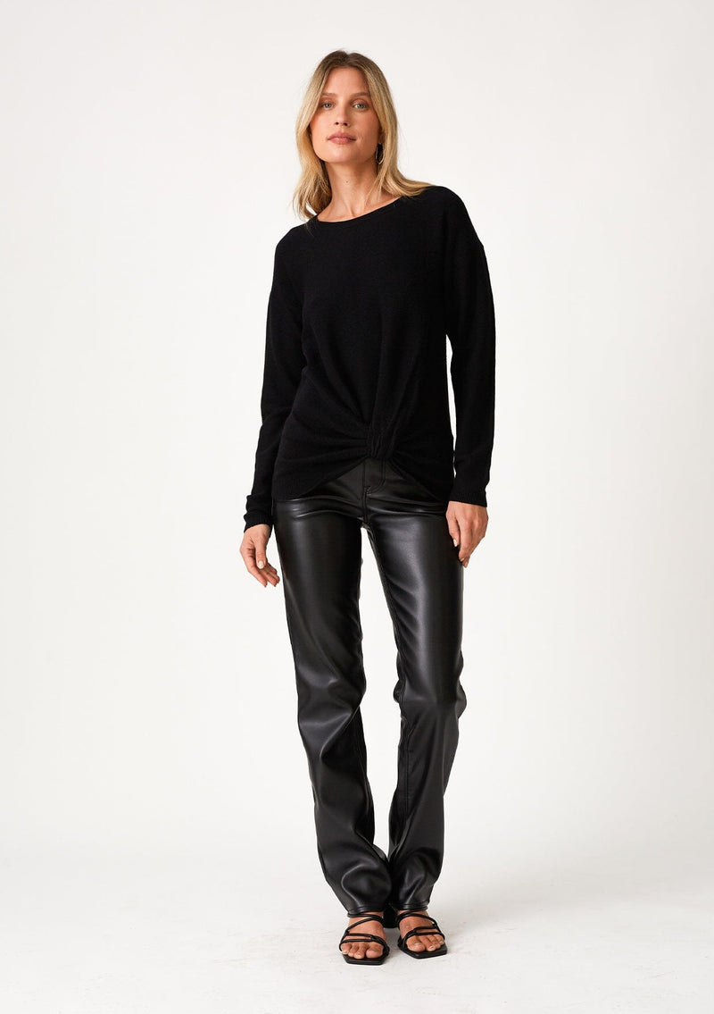 [Color: Black] A full body front facing image of a blonde model wearing a black pullover sweater in a ribbed textured knit. With long sleeves, a crew neckline, long sleeves, a relaxed fit, and a knot front waist detail.