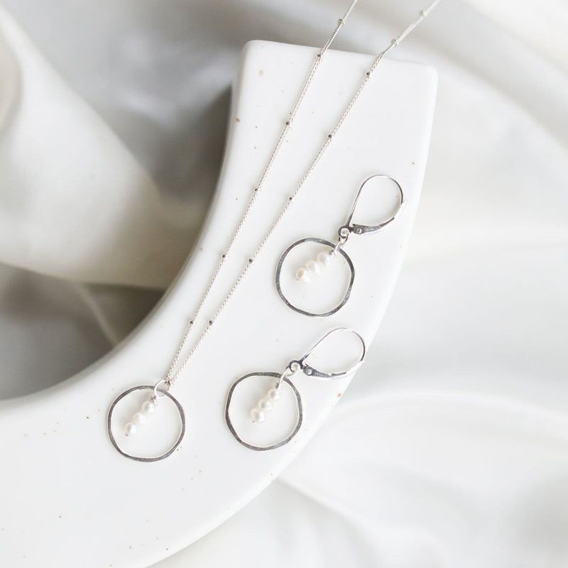 Sterling silver necklace with a circular pendant featuring three fresh water pearls suspended by a delicate beaded chain. 