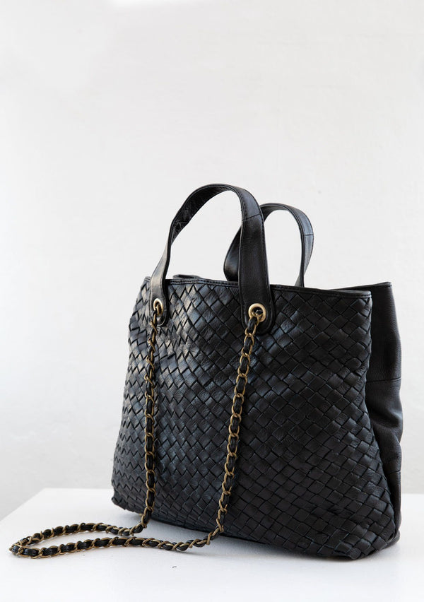 [Color: Black] A luxurious black leather bag with one woven side and one patchwork side. With two leather top handles, an adjustable leather chain long crossbody strap, an exterior zip pocket, and interior pockets. 