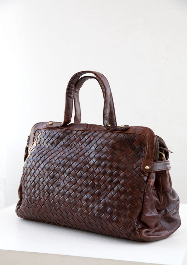 [Color: Brown] A luxurious brown woven leather bag. With two zippered compartments, a removable long leather crossbody strap, two leather top handles, and an exterior zippered pocket. 