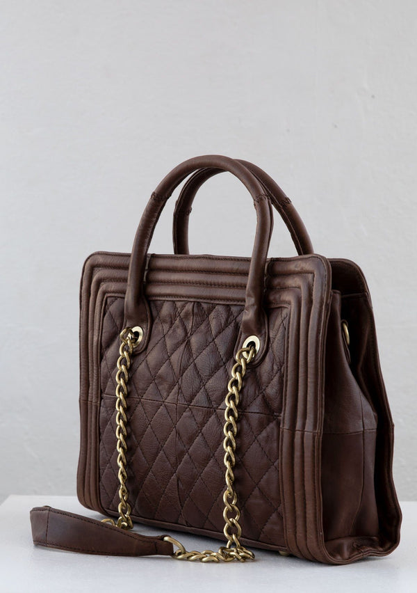 [Color: Brown] A genuine brown leather purse with a quilted exterior, leather top handles, a leather piping border, and chain straps. 