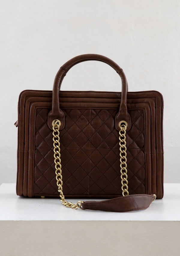 [Color: Brown] A genuine brown leather purse with a quilted exterior, leather top handles, a leather piping border, and chain straps. 