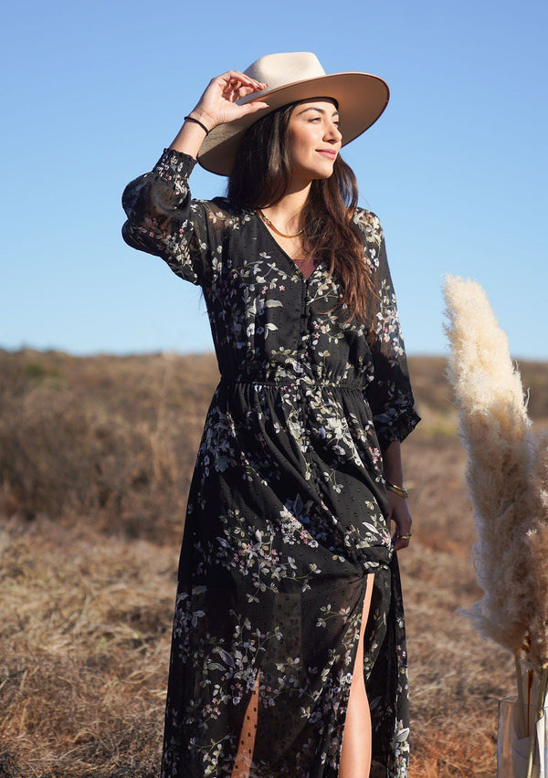 [Color: Black Slate] The ultimate romantic Autumn dress is here. Our bohemian floral print maxi dress is designed in a delicate sheer clip dot. Featuring a self covered button up front, a cinched elastic waist for definition, and voluminous long sleeves with a smocked elastic wrist cuff. A gorgeous day to night maxi dress. 