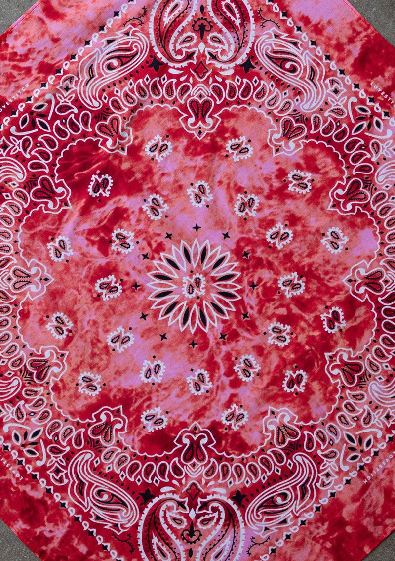 [Color: Red] A woman wearing a square bandana with a classic paisley print throughout in a trendy tie dye wash. 