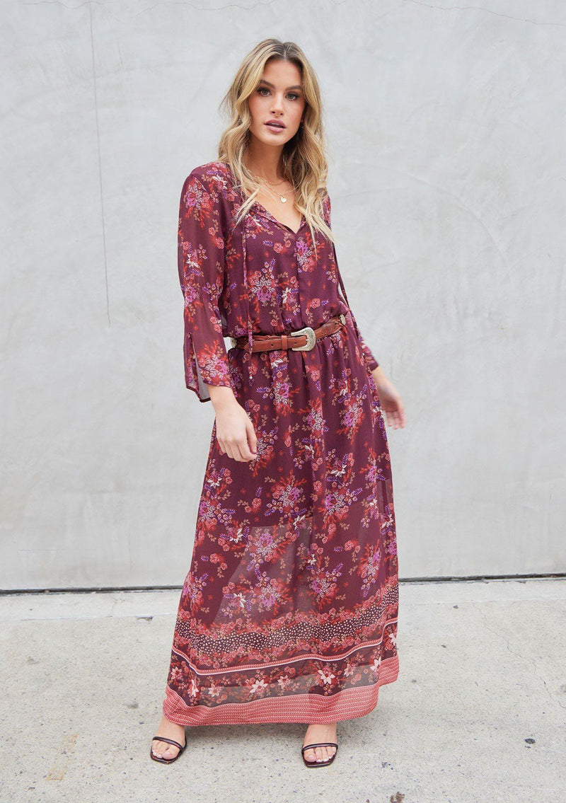 [Color: Wine Spice] A bohemian maxi dress in pretty mixed florals. Featuring a split v neckline with ties, a cinched elastic waist, and long bell sleeves with a split cuff.