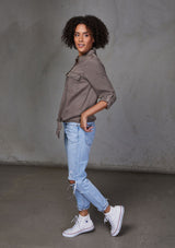 [Color: Mushroom] An ultra soft tie front top, featuring front flap patch pockets, button tab rolled sleeves and a trendy tie front detail. Paired here with denim.