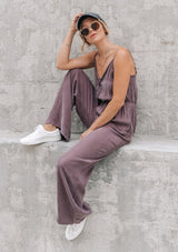 [Color: Charcoal] A woman wearing a one piece jumpsuit. Featuring a wide leg, a front keyhole detail, an elastic cinched waist, and side pockets.