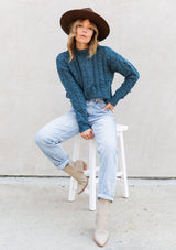 [Color: Teal] A gorgeous cable knit pullover featuring whimsical pom pom details, a warm mock neck, and a contrast ribbed trim.