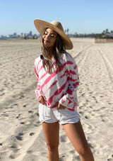 [Color: White Hibiscus] A woman on the beach wearing a soft and cozy tie dye sweatshirt. This cozy pullover features long raglan sleeves and a classic crew neckline. A great option for working from home.