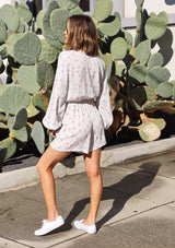[Color: Ivory/Coral] Girl wearing a white polka dot long sleeve short romper.