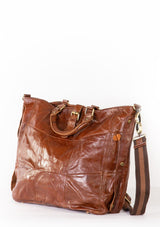 [Color: Brown] A brown quilted leather bag with detachable long strap, leather top handles, a buckled closure, and zippered interior compartment.