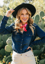 [Color: Dark Indigo] A classic denim blue button up shirt, featuring two front patch pockets with a button flap closure, a snap button up front, and a western style yoke. A staple button up style that pairs effortlessly with white denim. Worn here with a red bandana.