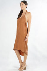 [Color: Bronze] A side facing image of a brunette model wearing an olive green high-low halter dress featuring a v-neckline, open back, side pockets, and an adjustable drawstring tie at the back for a chic finish.