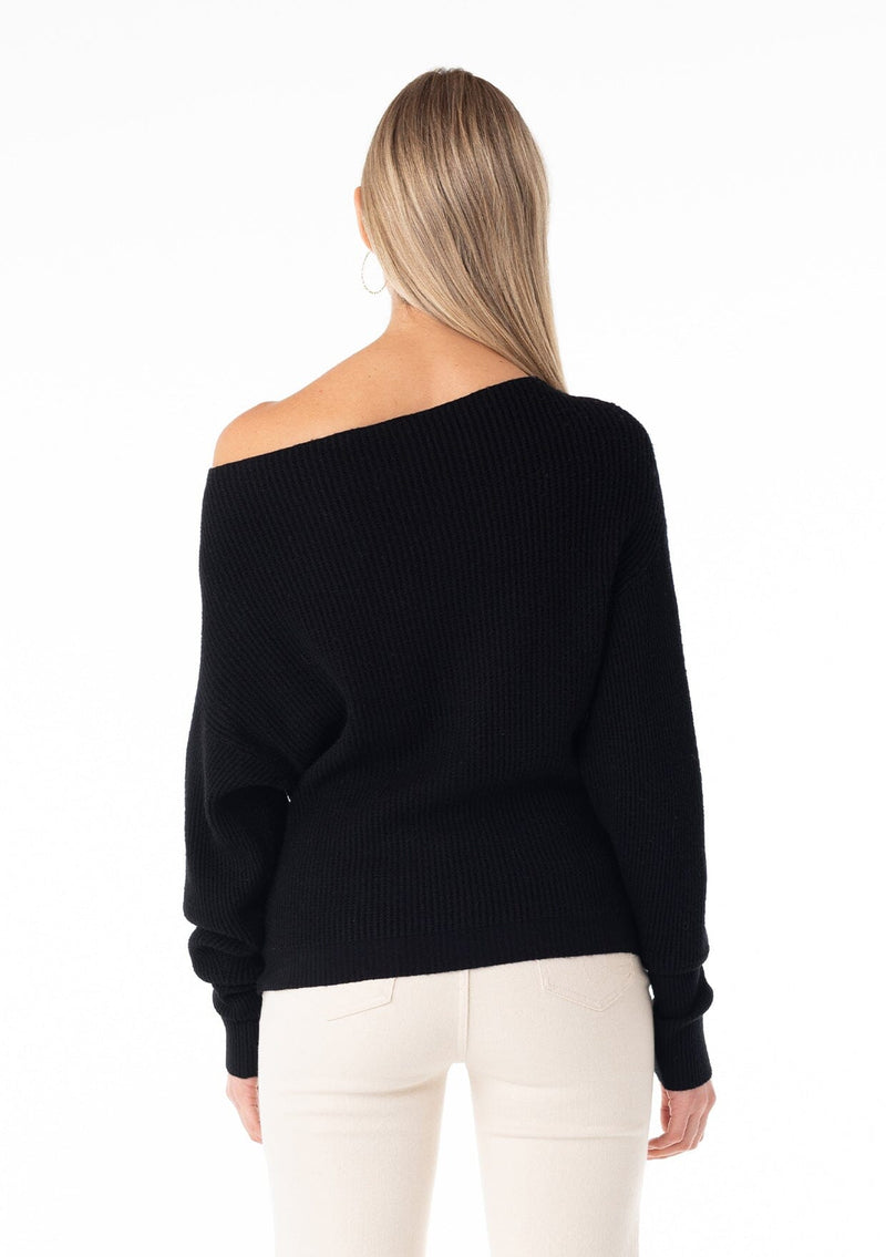 [Color: Black] A back facing image of a blonde model wearing a black waffle knit pullover sweater. With long sleeves, a relaxed fit, and a wide neckline that can be worn off the shoulder.