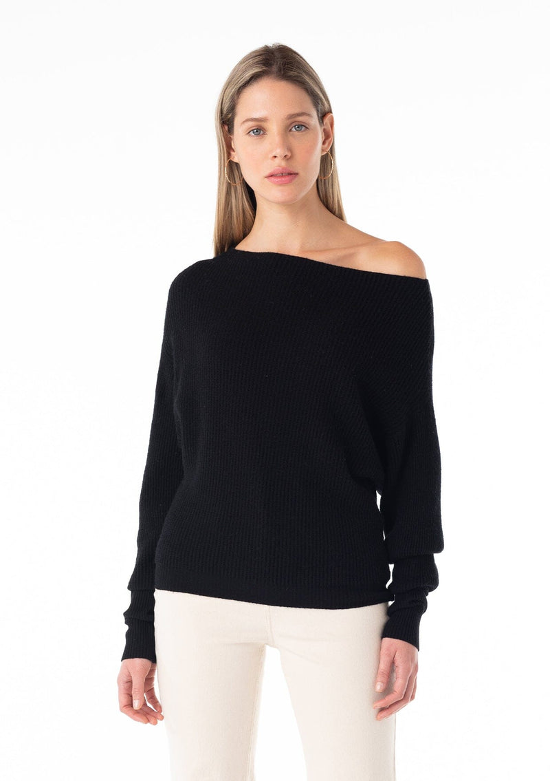 [Color: Black] A front facing image of a blonde model wearing a black waffle knit pullover sweater. With long sleeves, a relaxed fit, and a wide neckline that can be worn off the shoulder.