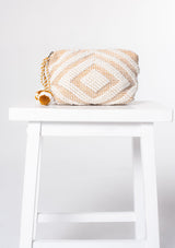 [Color: White/Saddle] A white and brown bohemian carpet makeup bag with pom tassel. 