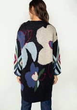 [Color: Navy Multi] A front facing image of a brunette model wearing a warm fall bohemian mid length cardigan in a multicolor large floral jacquard design. With long sleeves and an open front. 