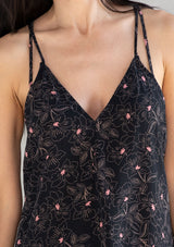 [Color: Black/Rose] A model wearing a black and pink floral tank top with racerback detail, a v neckline, and a strappy tie neck. 