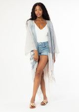[Color: Neutral Combo] A front facing image of a black model with long wavy hair wearing a cotton bohemian kimono with neutral blue and white white detail and fringe hemline. The kimono is open at the front.  