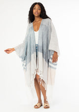 [Color: Neutral Combo] A front facing image of a black model with long wavy hair wearing a cotton bohemian kimono with neutral blue and white white detail and fringe hemline. 