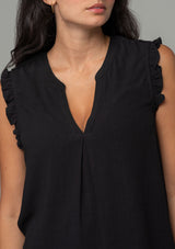 [Color: Black] A close up front facing image of a brunette model wearing a black linen blend bohemian top with short ruffled cap sleeves, a v neckline, and a flowy silhouette.
