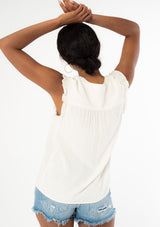 [Color: Natural] A back facing image of a black model wearing a natural, off white linen blend bohemian top with short ruffled cap sleeves, a v neckline, and a flowy silhouette. 