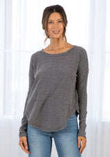[Color: Charcoal] A model wearing a charcoal cotton jersey stripe long sleeve tee with a wide crew neckline, a dropped shoulder, and a raw hemline. 