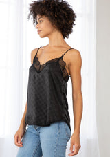 [Color: Black] A model wearing a black checkered jacquard silky slip camisole. With adjustable spaghetti straps and a lace trim v neckline and racerback. 