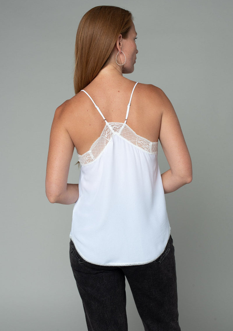 [Color: Chalk] A model wearing a timeless silky white lace trim camisole, perfect for layering or on its own. With a flattering v neckline and sexy racerback.