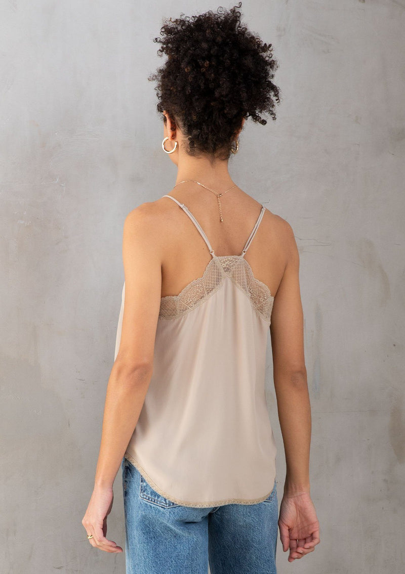 [Color: Stone] A model wearing a timeless silky taupe lace trim camisole, perfect for layering or on its own. With a flattering v neckline and sexy racerback.